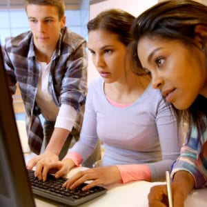 group of three college age students looking at computer screen