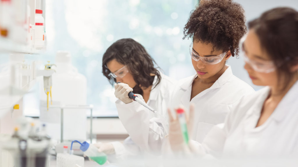 group of diverse female college students working in science lab